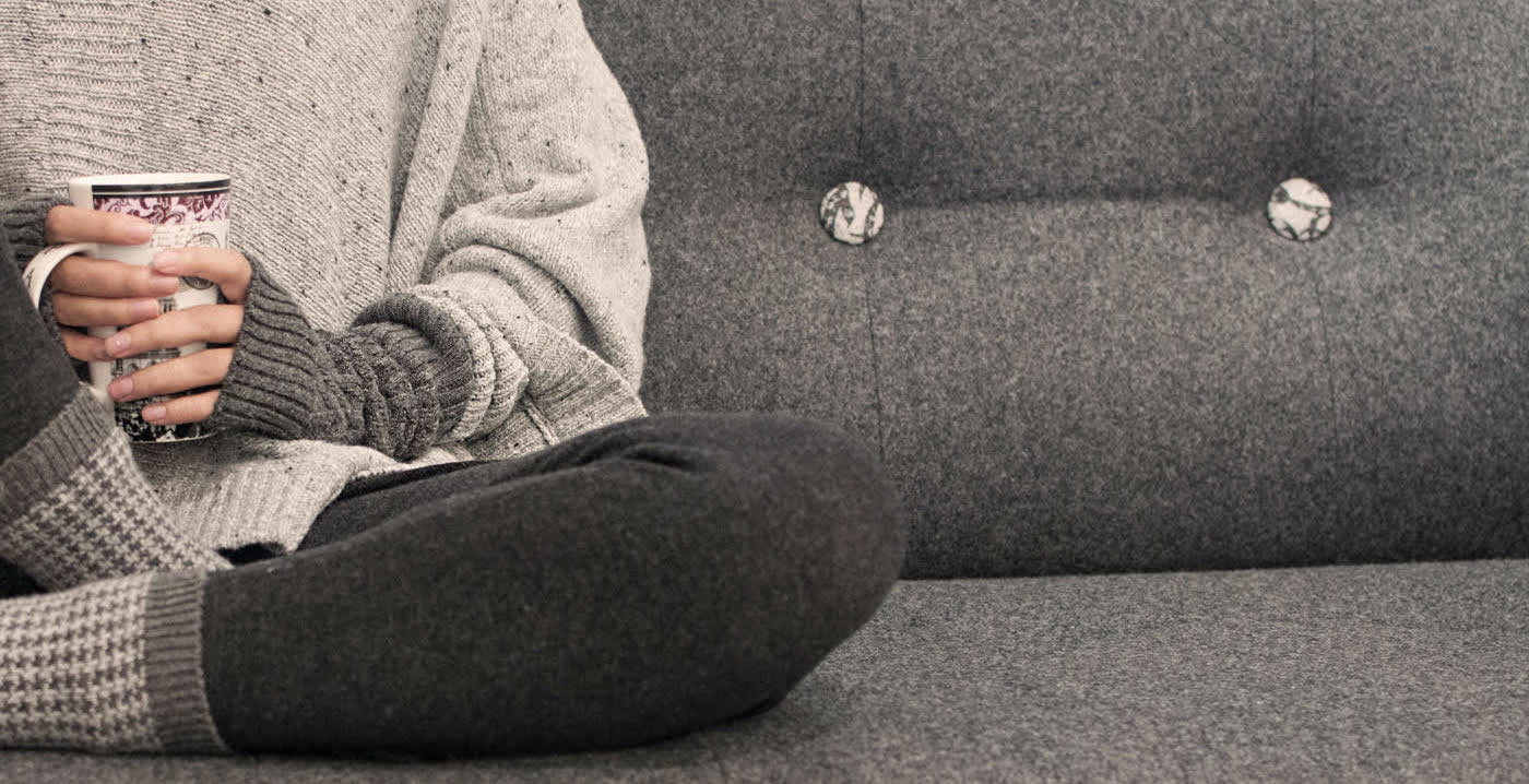 girl with a tea cup sitting on a gray sofa